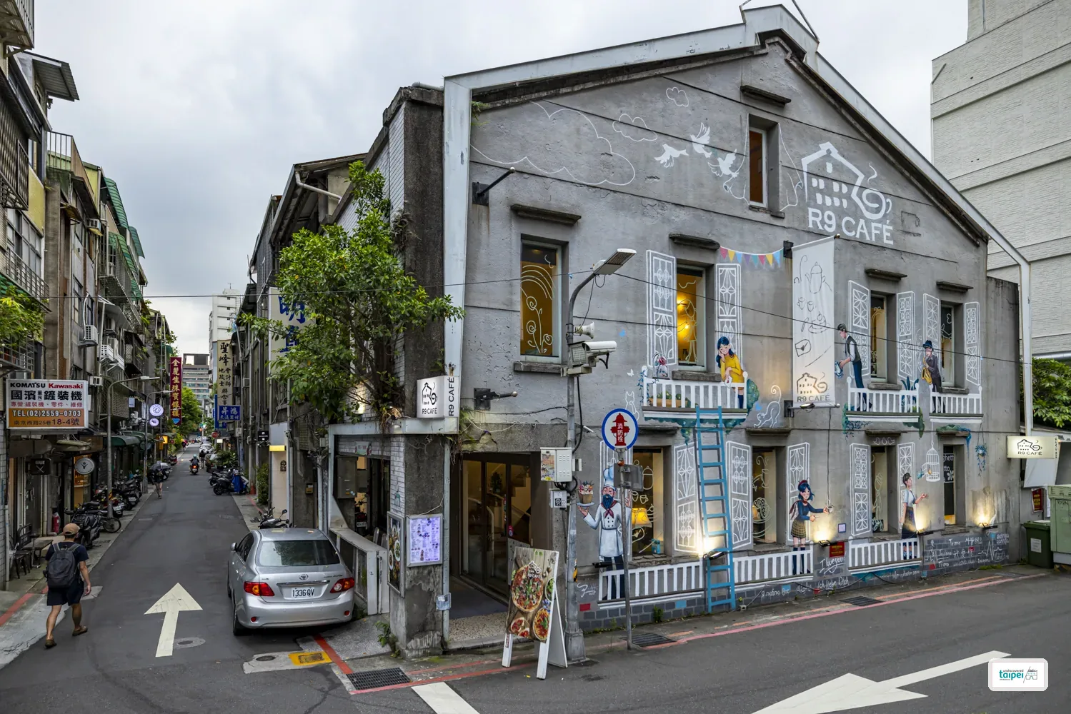The hand-painted mural facade of R9 Café on a corner of Chifeng Street, with the old lane stretching off to the left