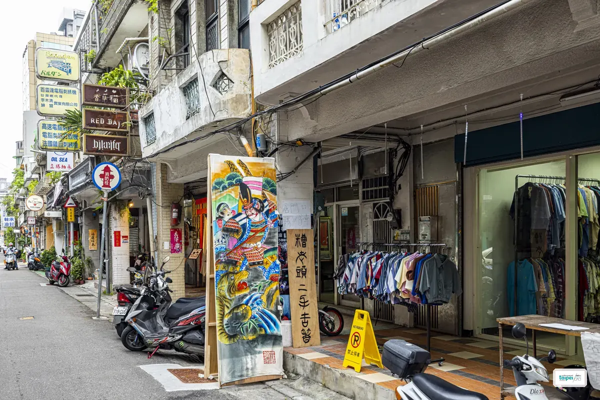 Racks of second-hand vintage shirts outside a shop on Chifeng Street, beside a hand-painted folk-art panel