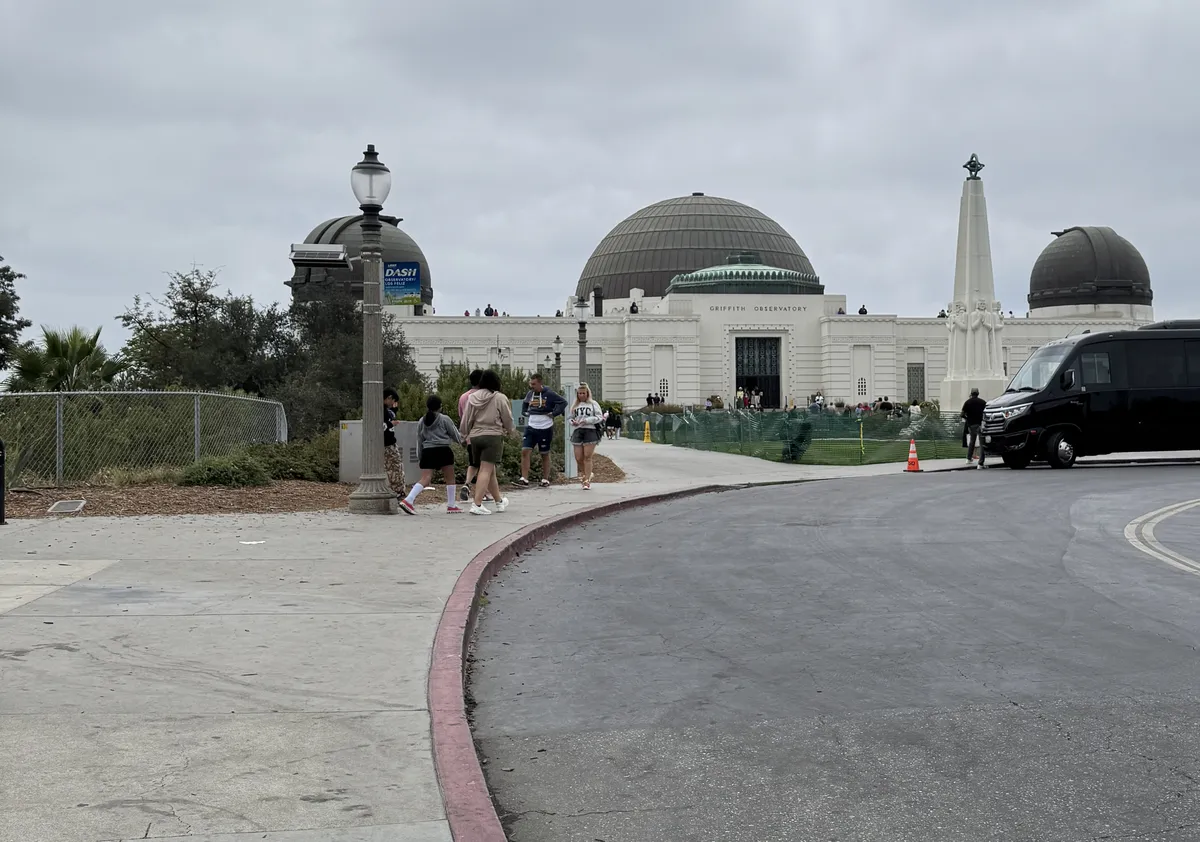Griffith Observatory domes with the rideshare and shuttle drop-off area on the road below
