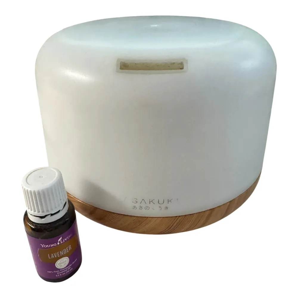 White ASAKUKI essential oil diffuser with a wood-look base next to a small bottle of Young Living Lavender essential oil