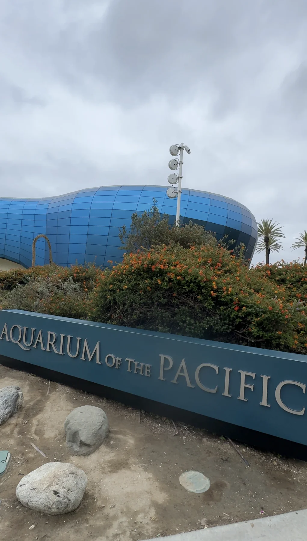 The Aquarium of the Pacific entrance sign and its blue wave-shaped building in Long Beach, California